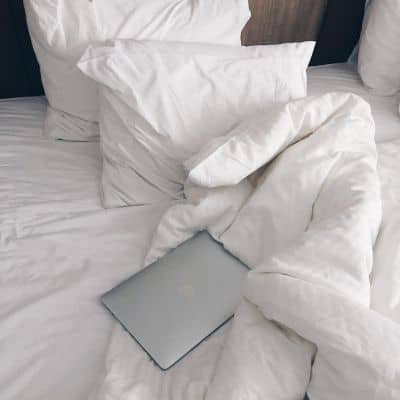 couette et oreillers sans housses sur lit défait