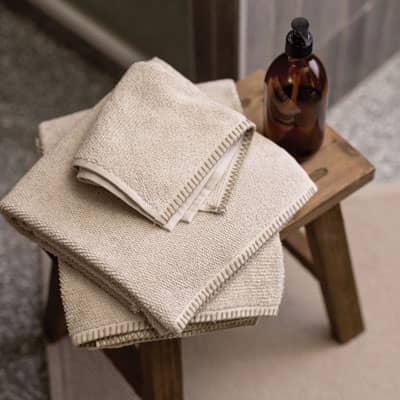 serviettes de bain écrues posées sur tabouret